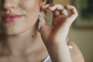 A young woman dressed for a party, the camera is focused on her jeweled earrings to reference capital gains tax